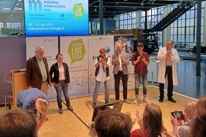 Großer Applaus für die Slammerinnen und Slammer und den Moderator (links) des Science Slams im Verkehrszentrum des Deutschen Museums im Rahmen der Münchner Wissenschaftstage 2023.