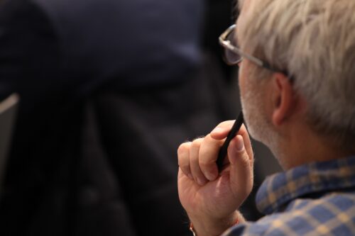 Ein Teilnehmer hört konzentriert den Vortragenden zu. Er hält dabei einen Stift in der Hand.